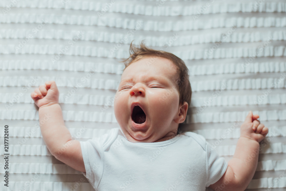 Infant baby sleeping and yawning on white sheets - obrazy, fototapety, plakaty 