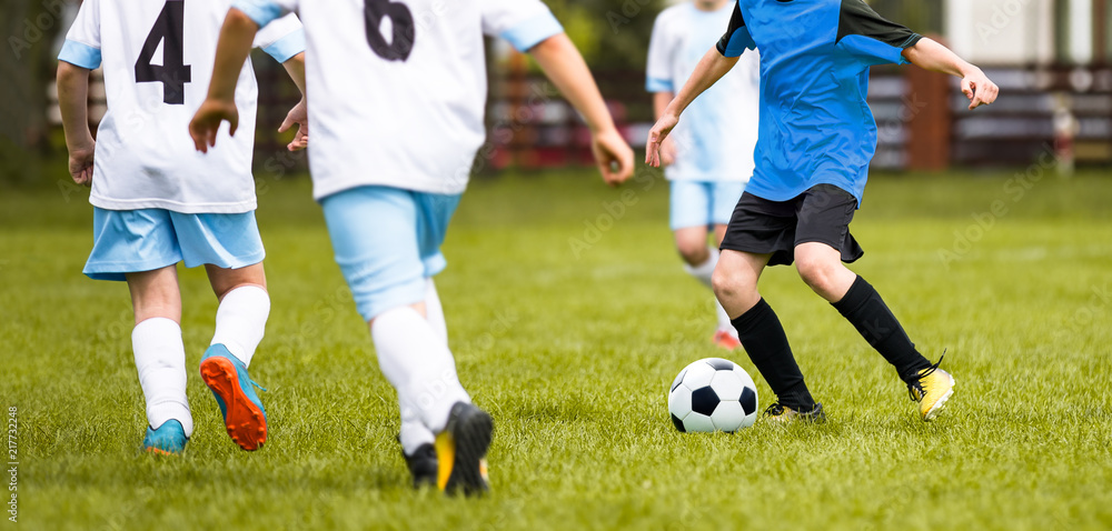 Obraz premium Young Junior Football Match. Players Running and Kicking Football Ball