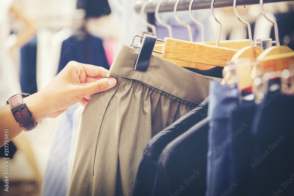 hand of customer choosing skirts in a clothing store - obrazy, fototapety, plakaty 