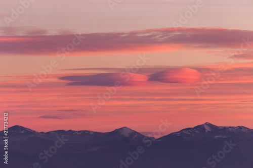 A view of some mountains top, beneath a beautiful, warm colored sky at sunset © Massimo