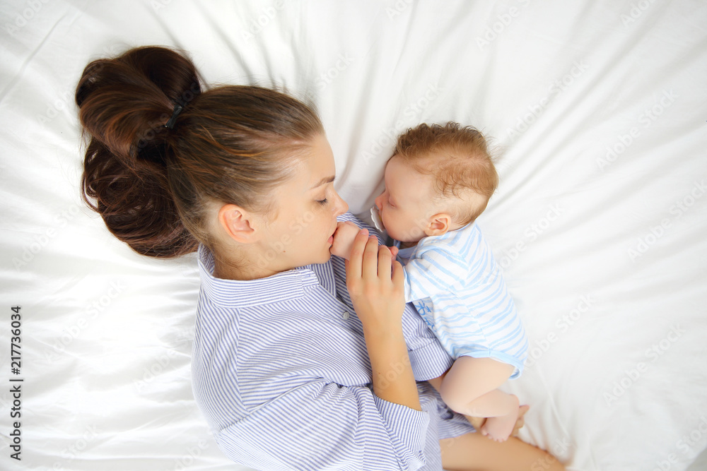 Portrait of a young mother and her sleeping 3 month old baby on the bed, concept of a shared dream. Top view Portrait of a young mother and her sleeping 3 month old baby on the bed, concept of a shared dream. Top view