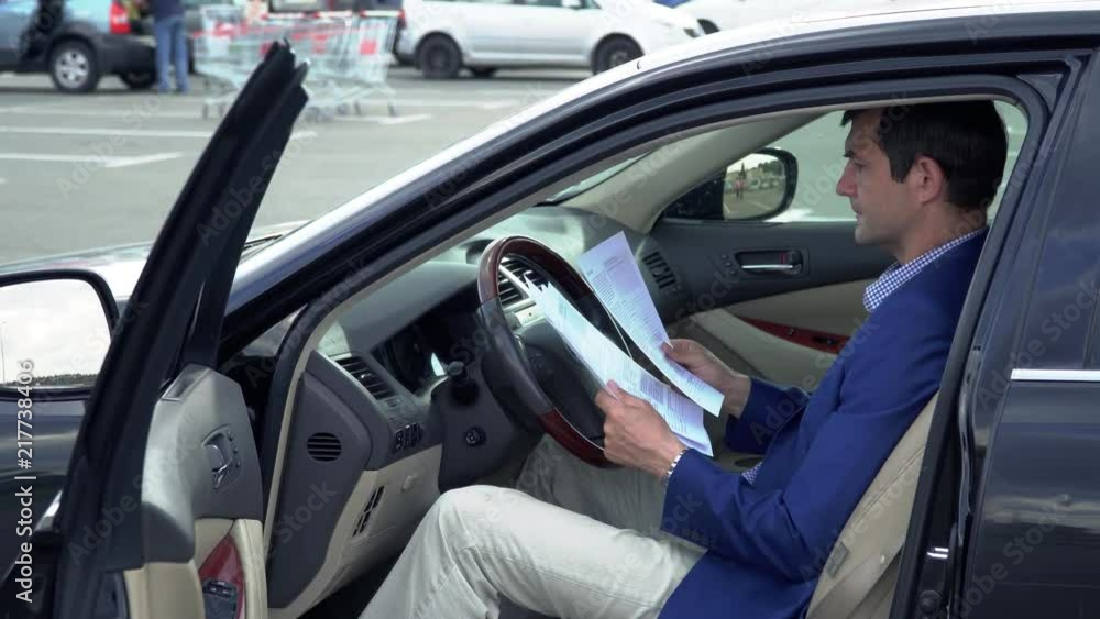 Business man sitting in the car and holding business papers in hands Business man sitting in the car and holding business papers in hands
