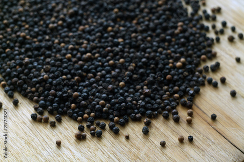 Black pepper close-up on wooden desk with blur effect.