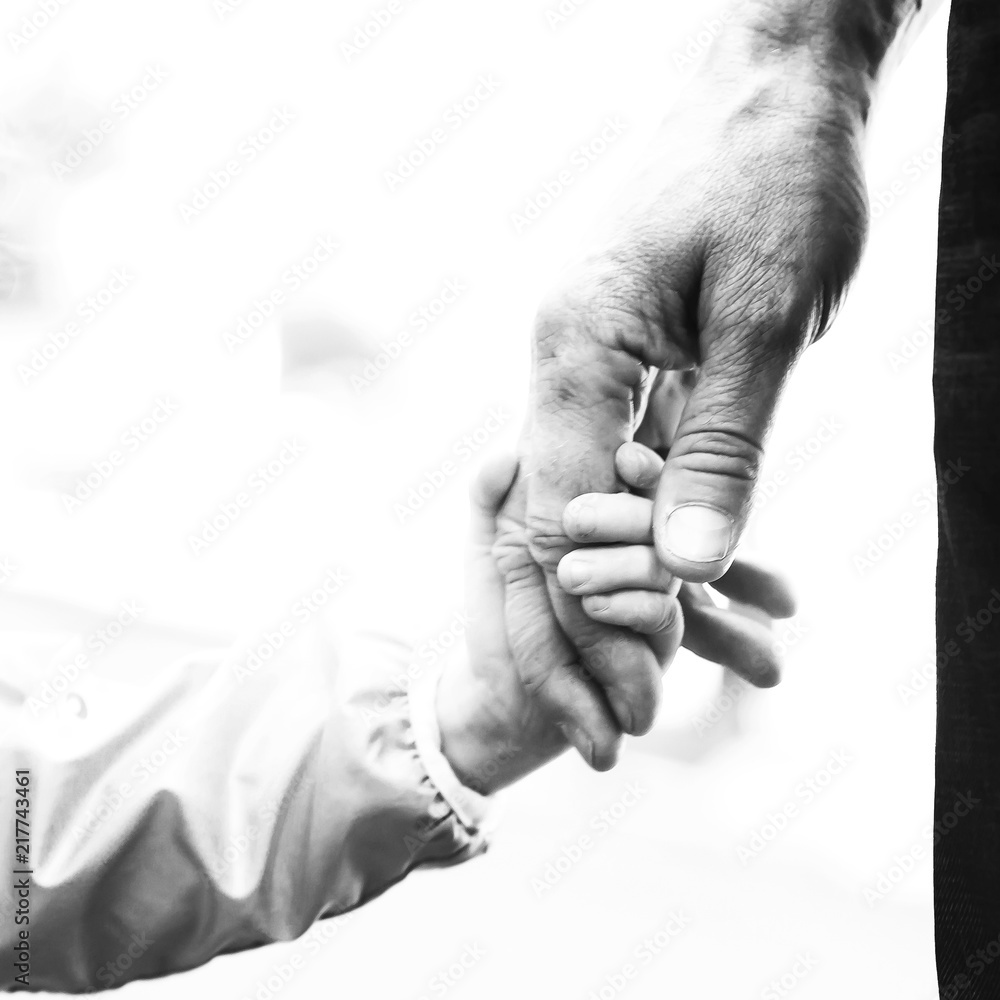 close up of child's hand holding a strong male hand