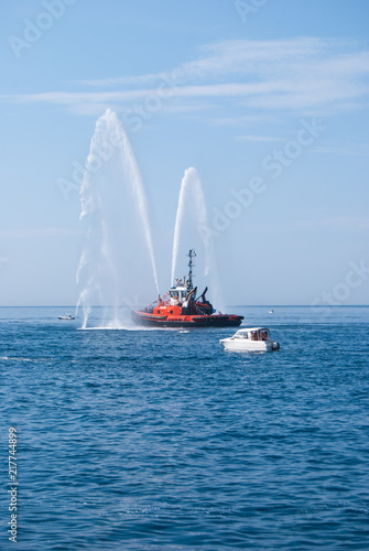 Naval vessel of firefighters with high splashes of sea water