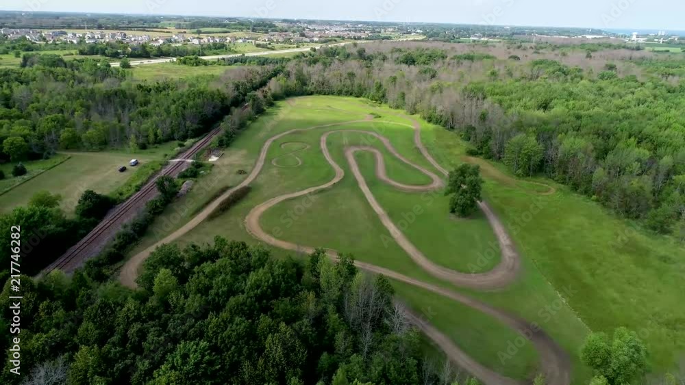 Aerial flyover of motorcycle dirt track hidden in woods along large lake. 11 seconds long Aerial flyover of motorcycle dirt track hidden in woods along large lake. 11 seconds long