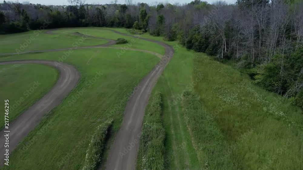 Aerial flyover of motorcycle dirt track hidden in woods along large lake Aerial flyover of motorcycle dirt track hidden in woods along large lake