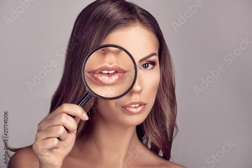 Pretty woman holding magnifying glass, focus on mouth