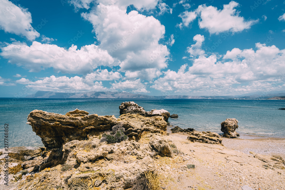 Panoramic view of rocks and beach with sky and clouds in Crete, Greece. Amazing scenery with crystal clear water and the rock formation against a deep blue sky during Summer period. Greece, Europe Panoramic view of rocks and beach with sky and clouds in Crete, Greece. Amazing scenery with crystal clear water and the rock formation against a deep blue sky during Summer period. Greece, Europe
