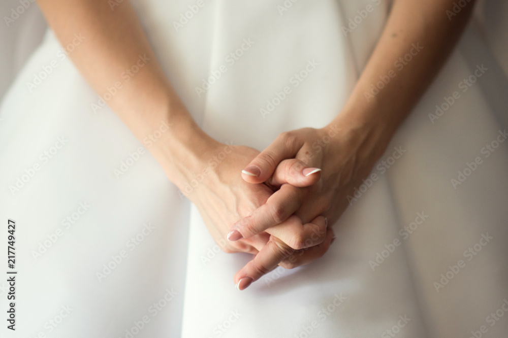 The crossed hands of bride in white wedding dress The crossed hands of bride in white wedding dress
