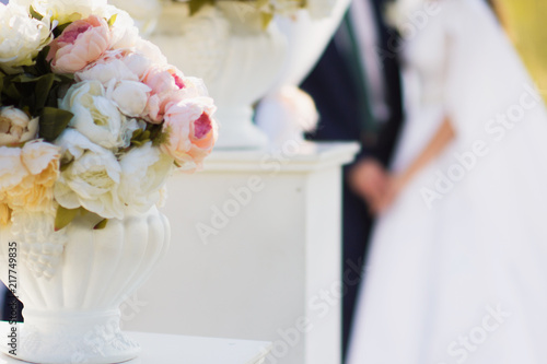 The bride and the groom on the backround. Floral decoration of wedding outdoor ceremony. Summer wedding, Happy married couple