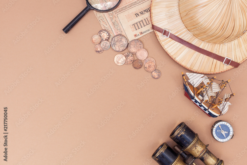 top view on items for travel, recreation and adventure: map, binoculars, straw hat, vintage paper and coins, magnifying glass, watch, compass, ship on beige background as a frame. flat lay - obrazy, fototapety, plakaty 