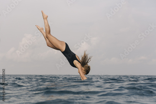 Side view of woman diving into sea against sky photo