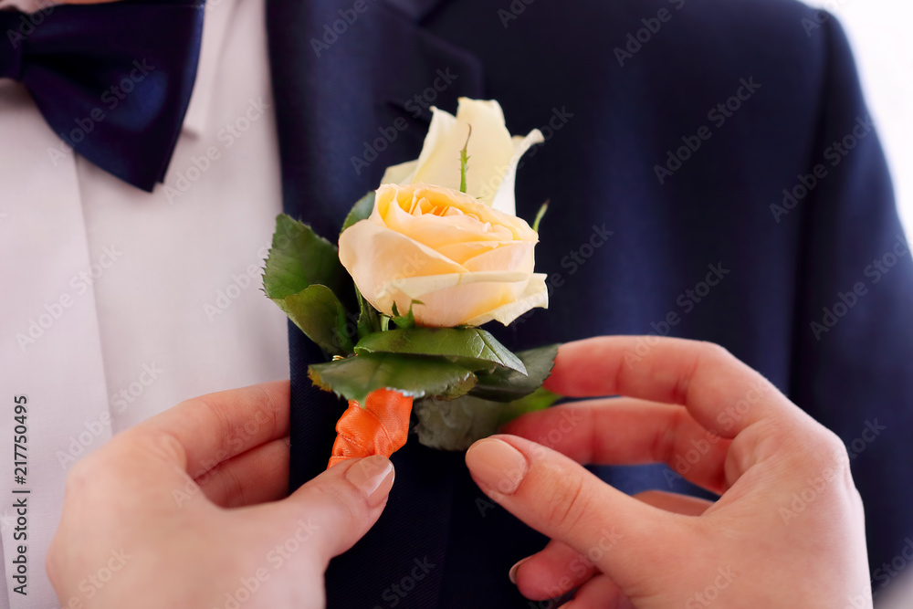 Bride pinning the rose boutonniere on suit jacket of wedding groom Bride pinning the rose boutonniere on suit jacket of wedding groom