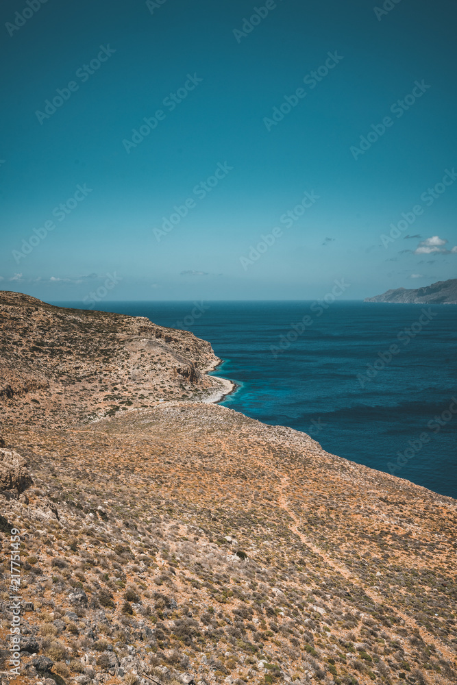 Panoramic view of rocks and beach with sky and clouds in Crete, Greece. Amazing scenery with crystal clear water and the rock formation against a deep blue sky during Summer period. Greece, Europe Panoramic view of rocks and beach with sky and clouds in Crete, Greece. Amazing scenery with crystal clear water and the rock formation against a deep blue sky during Summer period. Greece, Europe