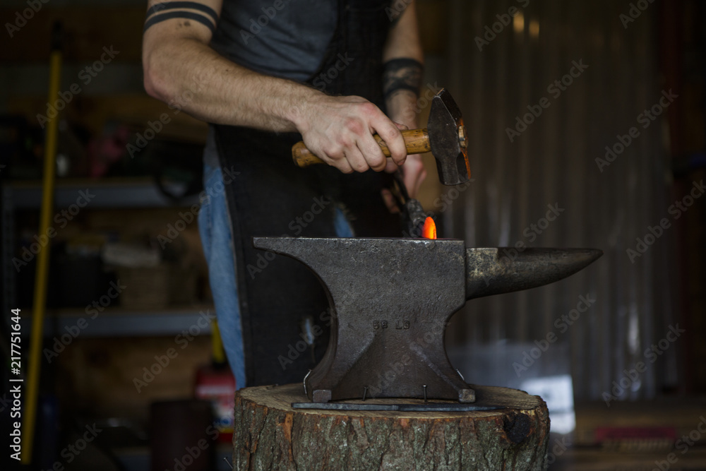 Midsection of blacksmith forging knife on anvil in workshop Midsection of blacksmith forging knife on anvil in workshop