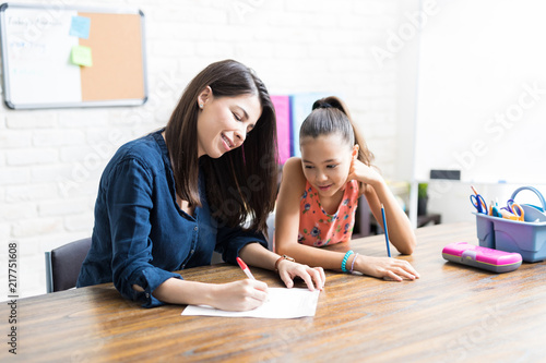 Mother Assisting Daughter With Schoolwork At Table photo