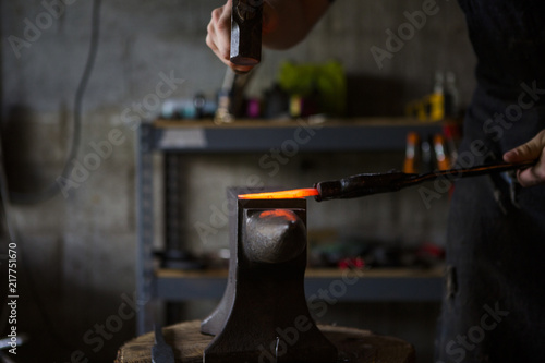 Blacksmith forging knife on anvil in workshop