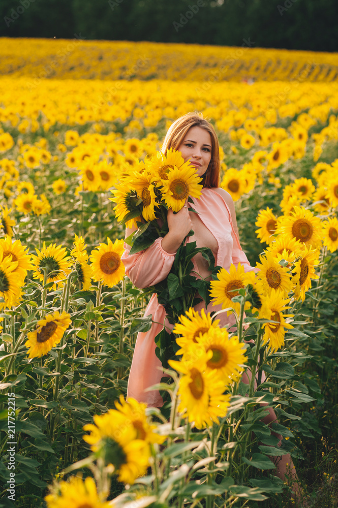 Beautiful girl in a huge yellow field of sunflowers.
