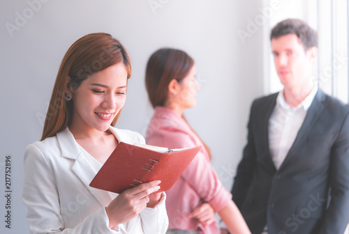 Business woman is reading notebook report with team on background