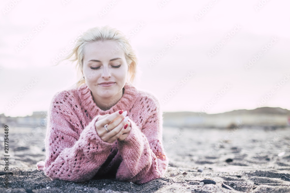 sweet attractive cheerful and thoughtful blonde yong woman lay down at the beach on the sand to enjoy the freedom and the leisure relax activity. outdoor with mountains in background sweet attractive cheerful and thoughtful blonde yong woman lay down at the beach on the sand to enjoy the freedom and the leisure relax activity. outdoor with mountains in background