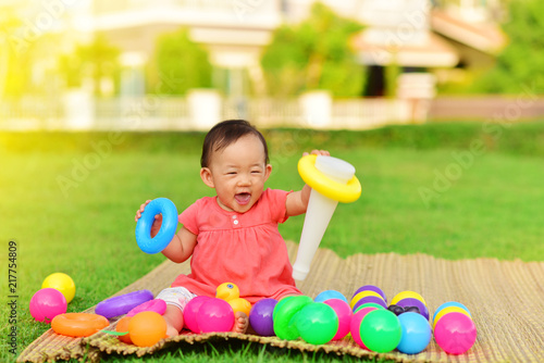 Cute Asian baby playing with toys in playground
