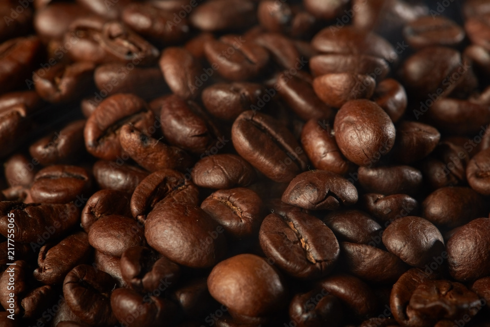 Naklejka premium grains of coffee with smoke on a dark background