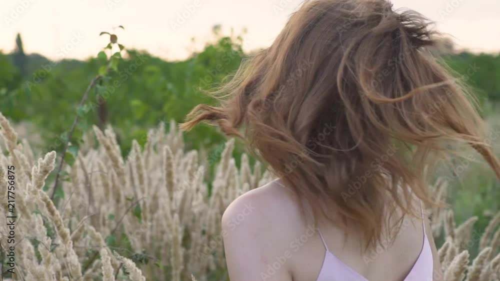 Close-up portrait of a young attractive red-haired woman in a field with spikelets. Slow motion Close-up portrait of a young attractive red-haired woman in a field with spikelets. Slow motion