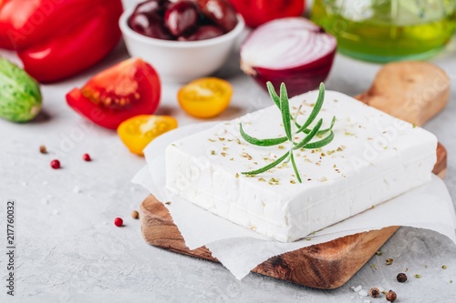 Homemade greek cheese feta with rosemary on wooden cutting board. Ingredients for greek salad