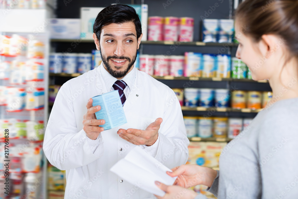 Male specialist is helping female client choose medicine in pharmacy.
