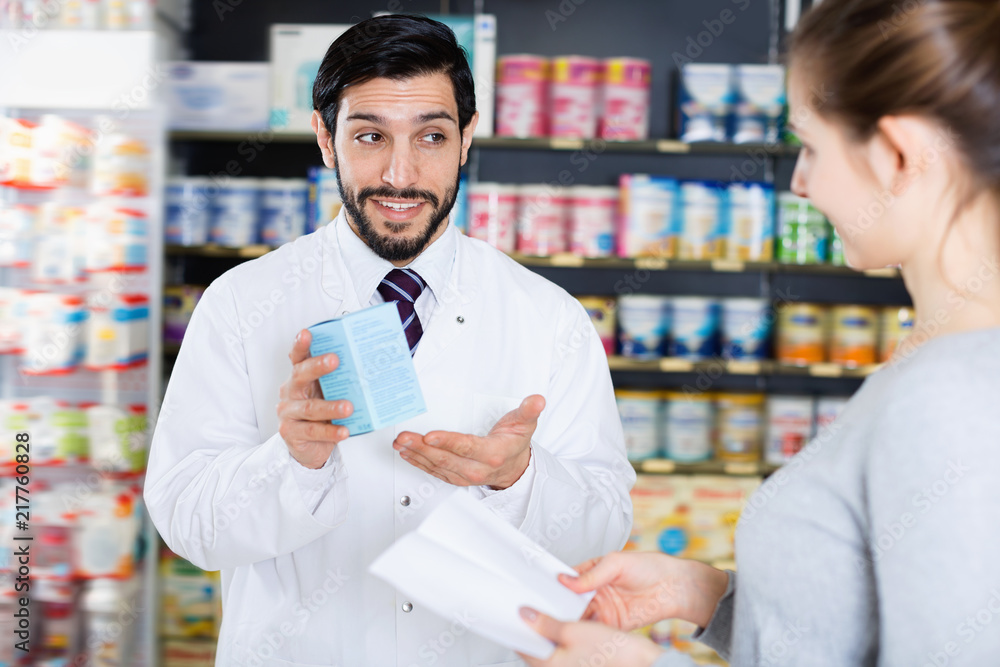Obraz premium Male specialist is helping female client choose medicine in pharmacy.