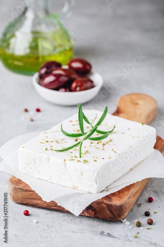 Homemade greek cheese feta with rosemary and herbs on wooden board