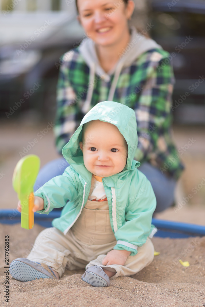 mother and child play in sandbox with green scoop mother and child play in sandbox with green scoop