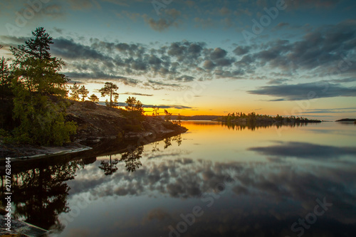 Dawn over the lake. The clouds are reflected in the water. Islands in the rays of dawn. Wild nature. Karelia. Russia. Nature of Russia.