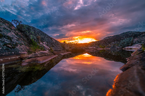 Sunset. The sun hid behind a rock. Reflection of the sky in the water. Karelia. Rocks of Karelia. Nature of Russia.