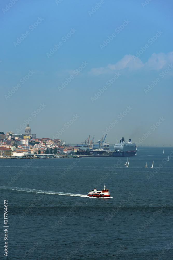 View of the skyline of the city of Lisbon with a traditional passenger boat (cacilheiro) on the Tagus River; Concept for travel in Portugal and visit Lisbon