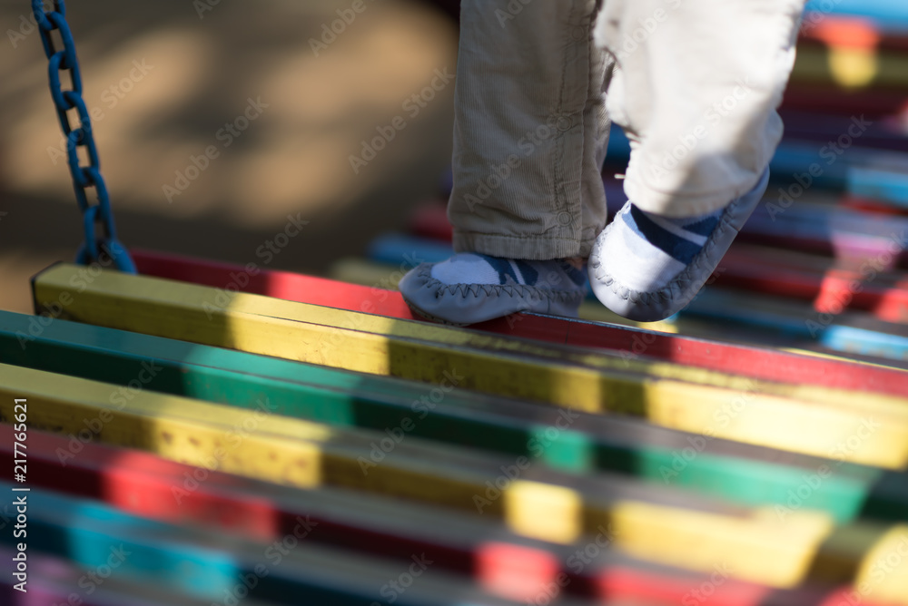 Baby's first steps on the playground. bridge of wooden multi-colored boards