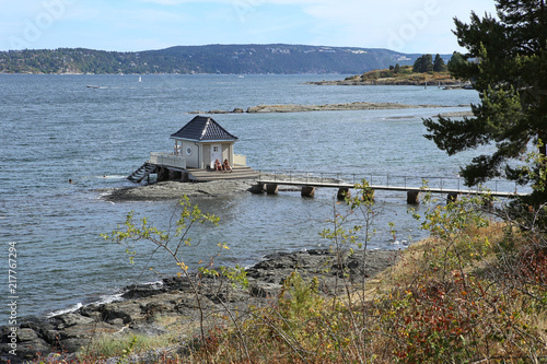 Lonely standing small cottage house in sea and footbridge connecting with coast in Oslofjord, Norway. View to Oslo fjord in Fornebu district in Oslo, Norway.