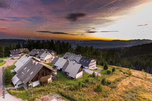 Resort mountain village houses surrounded foret at sunset. photo