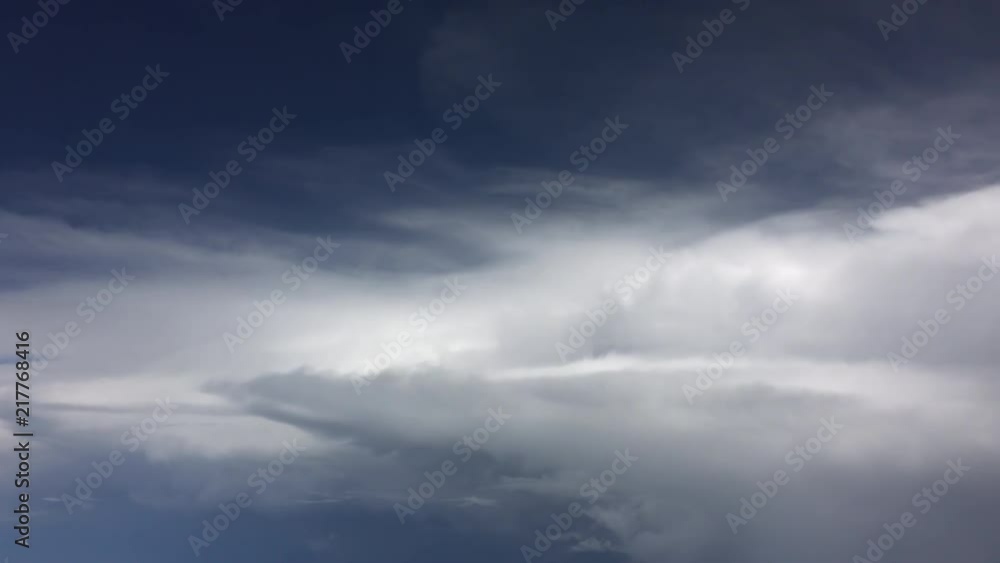 Aerial view of puffy white clouds in indigo blue sky filmed from window of passenger jet. Real time 4K. Aerial view of puffy white clouds in indigo blue sky filmed from window of passenger jet. Real time 4K.