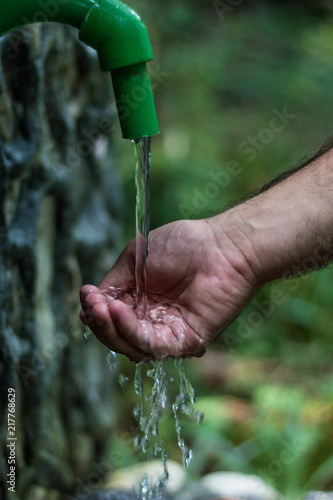 Hand beneath water coming from a tap (Zlaca, Bosnia)
