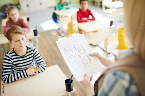 Obraz na plátně Oral questioning at math class: teacher holding paper with algebraic examples an