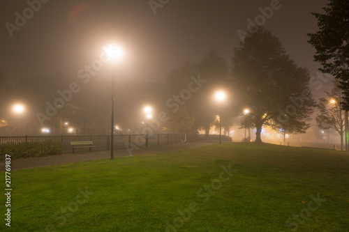 Empty park and streetlights at foggy night