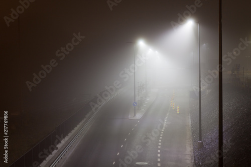 Empty road and streetlights at foggy night