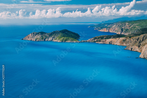 Coastline in front of Assos village and Frourio peninsular. Beautiful milky blue bay with brown rocky limestone costline and moving white clouds on horizon, Kefalonia island, Greece