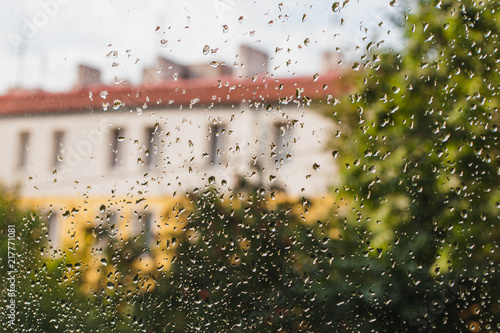 drops of autumn rain on the glass, autumn foliage and house background