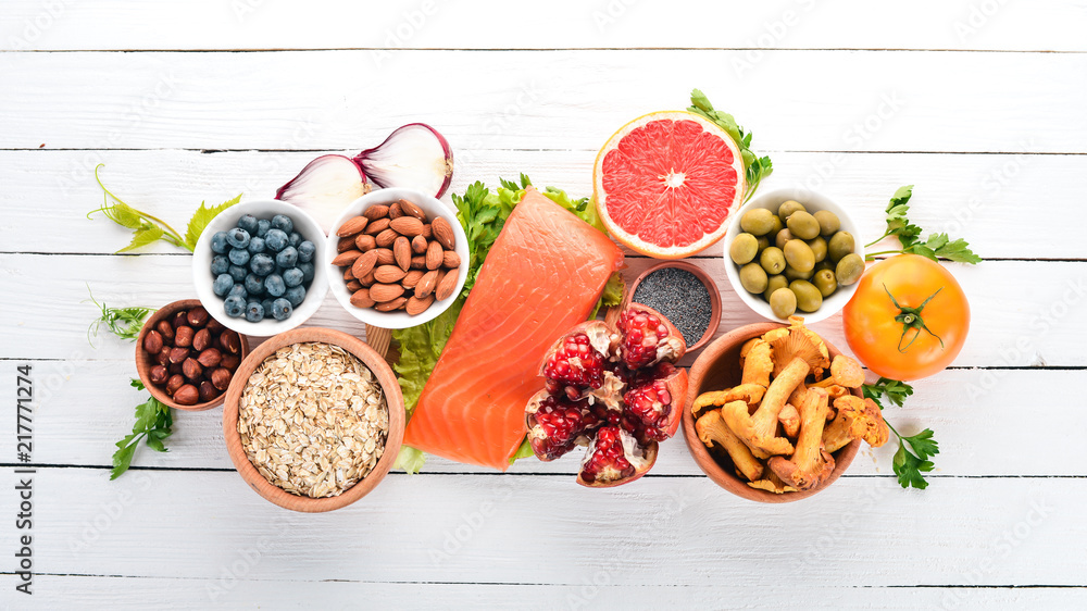 A set of healthy food. Fish, nuts, protein, berries, vegetables and fruits. On a white background. Top view. Free space for text.