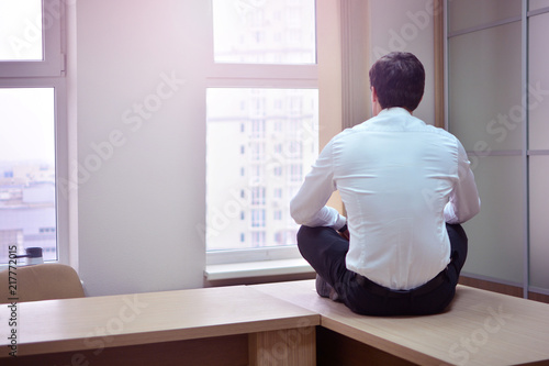 Dismissal from work background. A sad and frustrated office worker sits at his desk in an empty office. The concept of stress and depression in business.