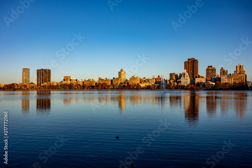 Upper Manhattan skyline view with reflection in lake and in sunset lights during the fall autumn season. Central park in New York, NY, USA