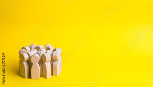 Group of wooden people figurines on a yellow background. Crowd, meeting, social activity. Society, social group. Herd instinct, management of people. Human resources, workers stand together.